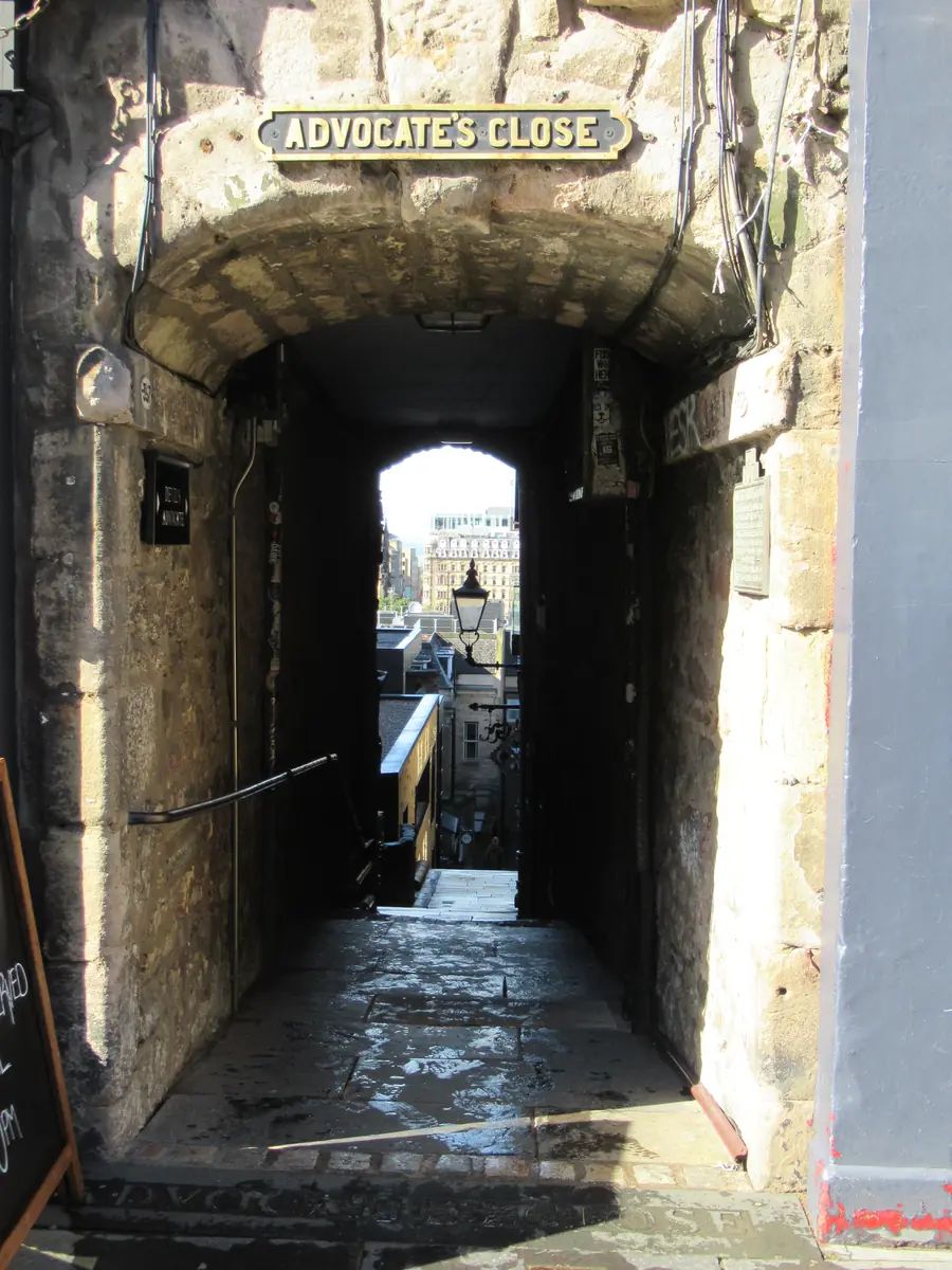 The stone archway into Advocate's Close off the Royal Mile, a narrow passage dropping steeply downhill towards a patch of daylight
