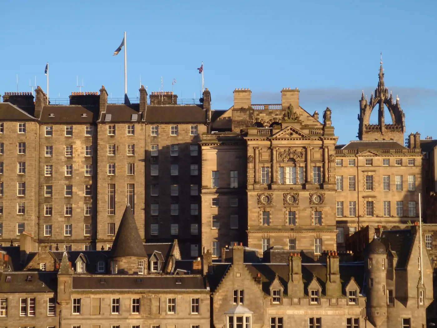 Edinburgh's Old Town in evening sun seen across the Mound, tall stone tenements stacked up the ridge below the crown spire of St Giles'