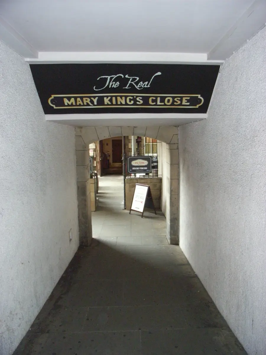 A white passage leading to the Mary King's Close tour, with a black and gold sign reading The Real Mary King's Close