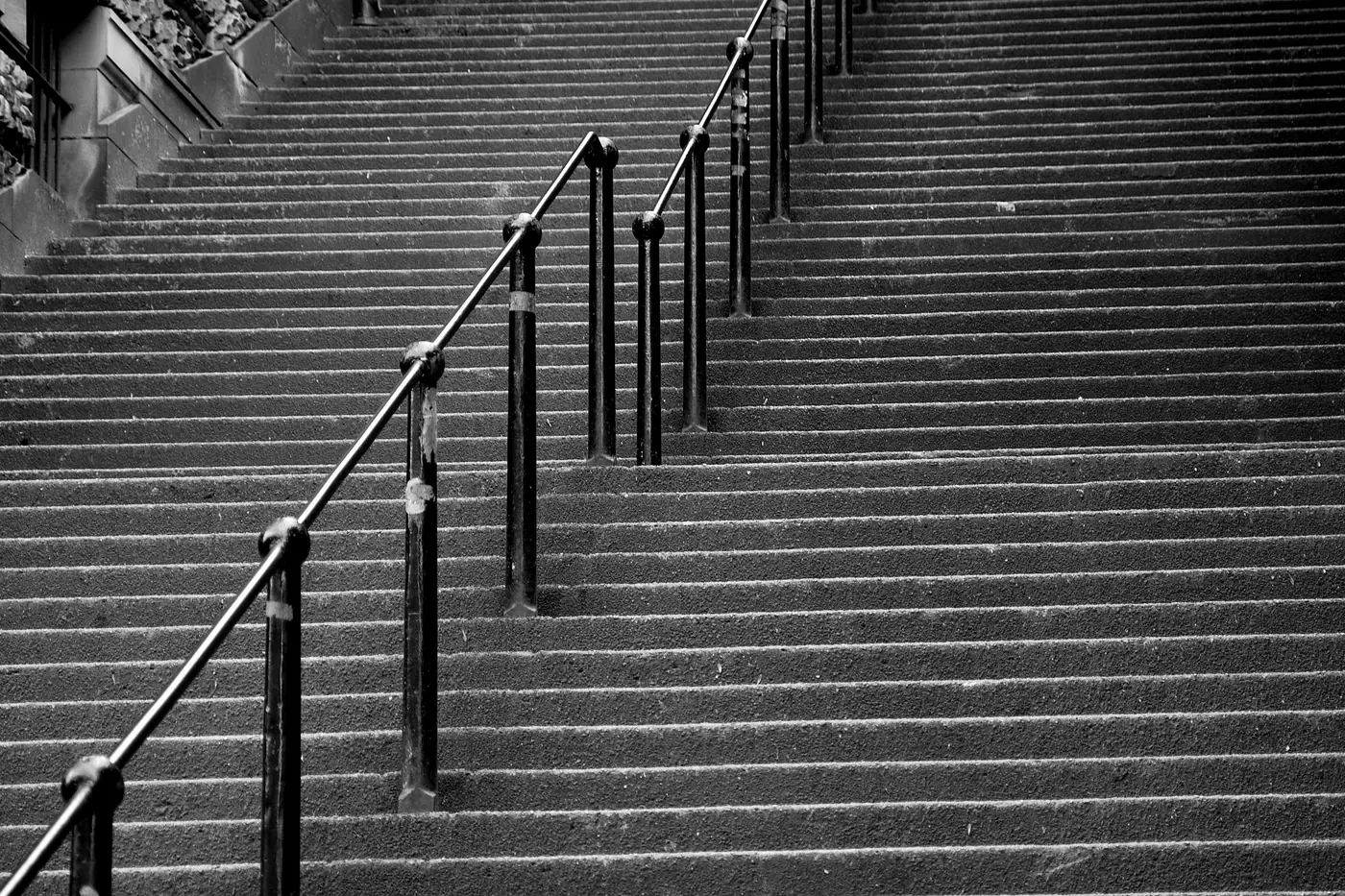 Black and white view of the long stone stairway of Warriston's Close with iron handrails running up the middle